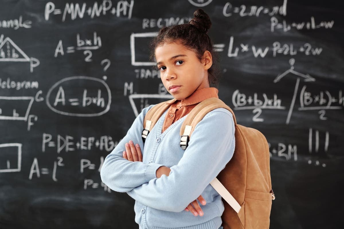 Matematik yazılı bir tahtanın önünde duran ortaokul öğrencisi